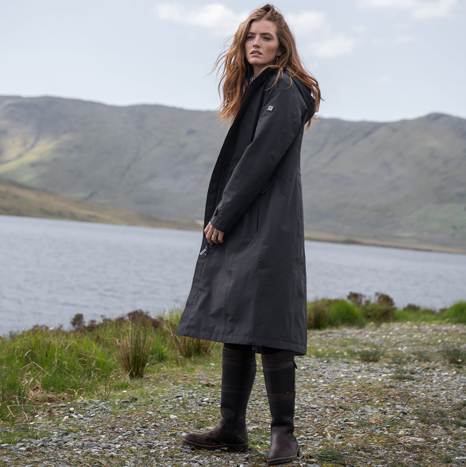 Lady in Dubarry waterproof jacket and boots against lake and mountain background