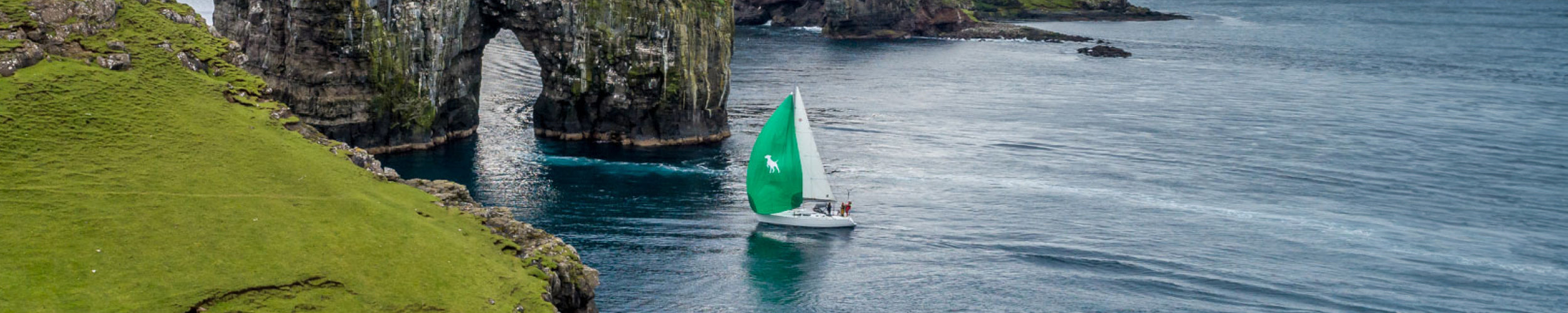 Wide image of the Barba Boat team and vessel off the coast in dark blue water next to some scenic coastline.